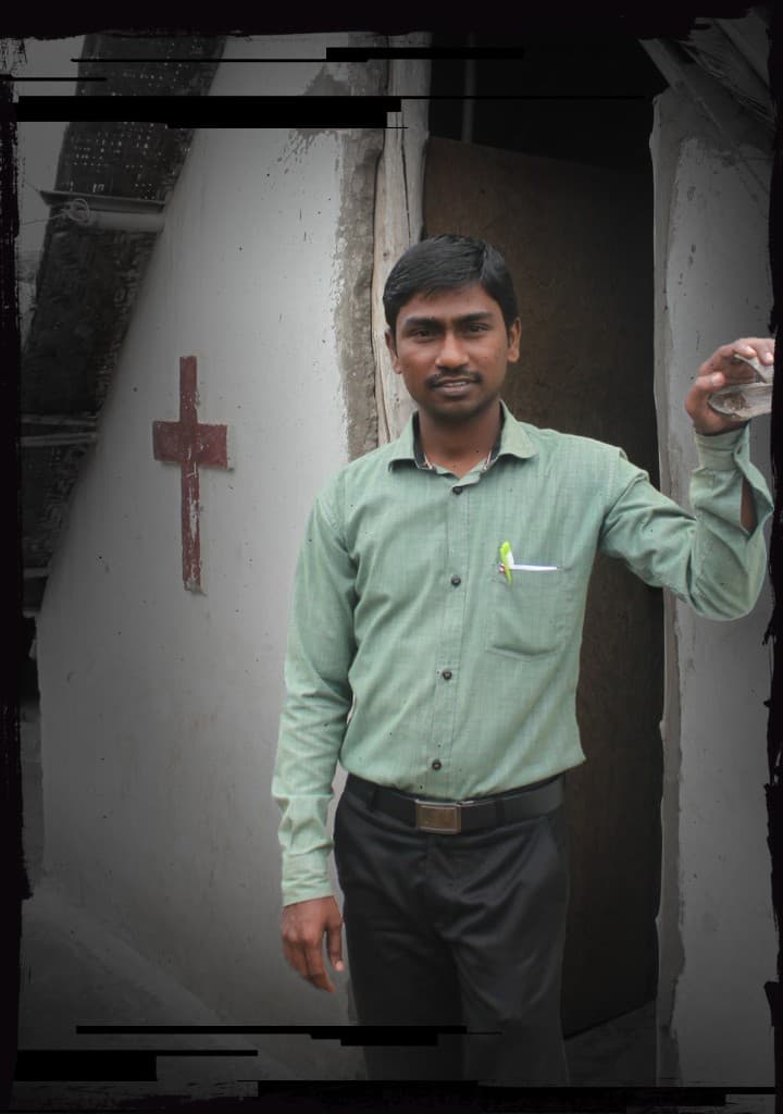 Pastor Kurian standing beside his church marked with a red cross